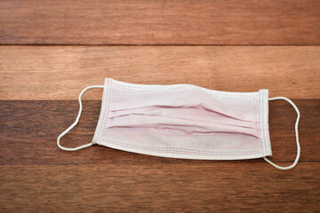 Pink face mask on wooden table texture background. 