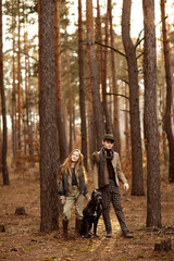 Fototapeta premium Girl and boy walk with a dog Cane corso in the forest and have a fun. Children stand near a tree and hold a dog on a leash.