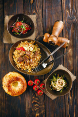 Traditional plov with lamb meat, garlic, onion and salads on the sides