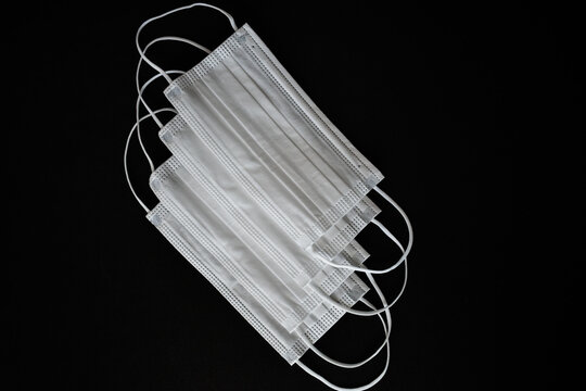 White surgical masks photographed on a black background