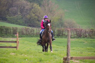 Young rider and her horse heading towards the camera at speed as they enjoy the freedom to move at speed across the countryside in Shropshire UK