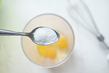 Fototapeta na wymiar a spoonful of sugar over the yolk. A teaspoon with salt