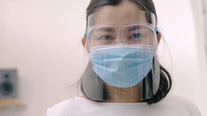 Portrait of an Asia young female who is wearing a face shield with mask rounded around her face from a frontal perspective to protect her glasses and eyes prepare to new normal. Coronavirus pandemic.