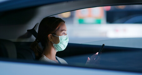 Woman wear medical mask and use of mobile phone sit inside the car