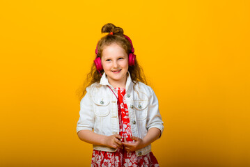 Happy carefree child emotions. Energetic joyful adorable little girl with headphones laughing at joke on yellow background.