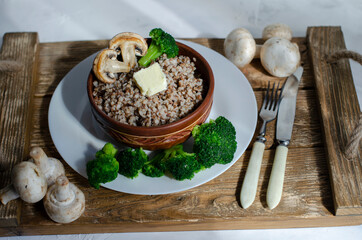 buckwheat porridge in a clay plate with butter and broccoli