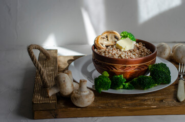 buckwheat porridge in a clay plate with butter and broccoli