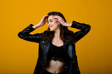 Portrait of a happy young brunette girl showing gestures and smiling, surprising isolated over yellow background. Emotional picture.