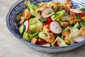 Traditional fattoush salad on a plate with pita croutons, cucumber, tomato,radish and herbs