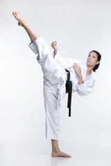 Black belt martial artist woman doing a high kick in her karate clothes.  © AnnaMarie