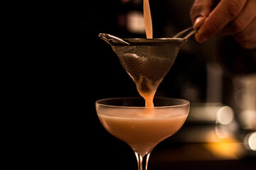 cocktail pored in glass through a strainer