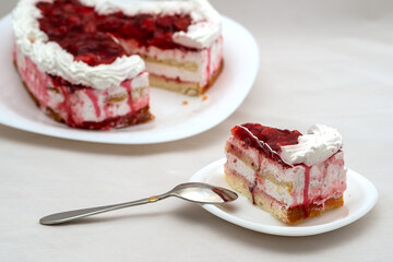 A cut piece of strawberry cake with cream in the shape of a heart for a holiday in a plate on the table. On the background of cake.