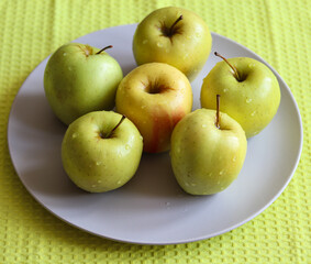 juicy ripe apples on a white plate close up
