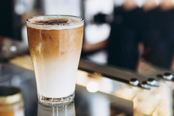 Glass with coffee, milk and ice on cafe background