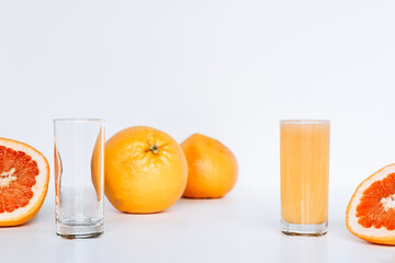 Glass with grapefruit juice and whole and sliced grapefruit on the background