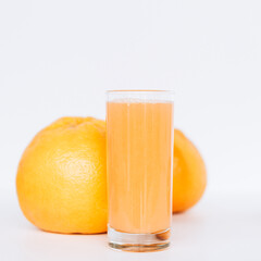 Glass with grapefruit juice and whole and sliced grapefruit on the background