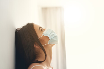 Pretty young model in mask standing at the wall in room