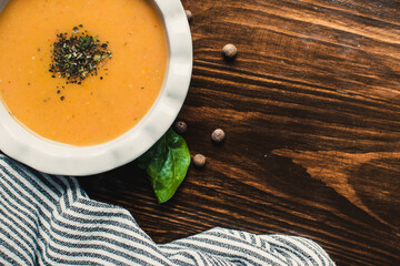 Pumpkin and carrot cream soup on the dark wooden table. Healthy food.