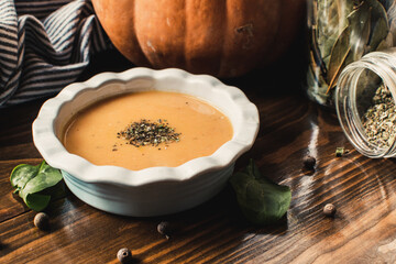 Pumpkin and carrot cream soup on the dark wooden table. Healthy food.