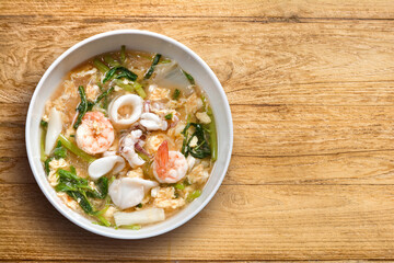 Sukiyaki, Shabu (Thai Suki) asian food in broth Mixed sea food with prawn, squid slide, eggs, vermicelli, vegetable, served with sesame & tofu mashed sauce, spicy sweet & sour, top view isolate wooden