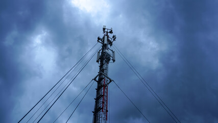 Telephone tower telephone signal, background stormy black clouds.              