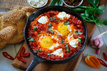 Shakshuka. Fried eggs in tomato sauce, with tomatoes and hot peppers, in a cast-iron frying pan.