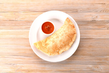 fried cheburek on a white plate with sauce
