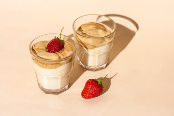 Dalgon coffee in a transparent glass with milk on a pastel background with strawberries