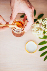 A man picks up a spoonful of thick fresh honey from a jar - top view - beekeeping