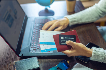 Man is buying air tickets over the Internet using a laptop for a trip. Online purchase and booking of travel tours