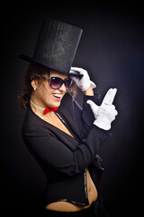 Beautiful emotional woman or girl in a black hat and a tailcoat and white gloves, in the image of a...