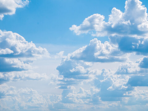 A lot of medium-sized fluffy clouds with a flat bottom against a large bright blue sky with a haze covered horizon