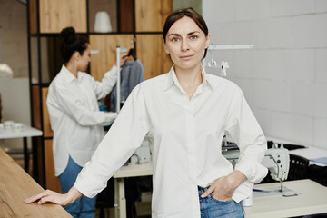 Fototapeta premium Pretty young fashion designer in white shirt standing in front of camera
