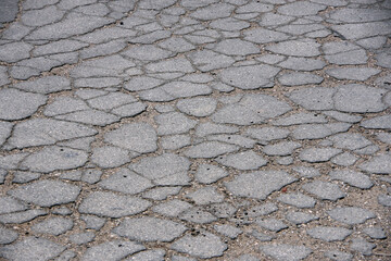 Close-up high angle full frame view of an area of old cracked and broken asphalt in a public alley
