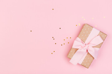 Gift or gift box and stars confetti on a pink table from above. Flat composition for birthday