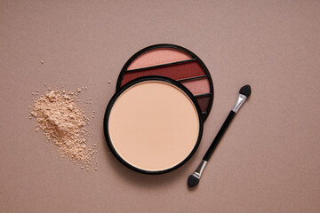 powder with professional face makeup and eyeshadows on beige background, close view, beauty concept 