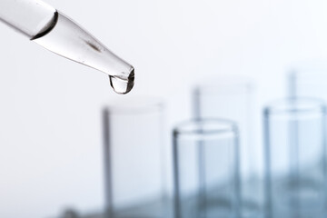pipette with a drop and scientific laboratory test tubes in a research laboratory.