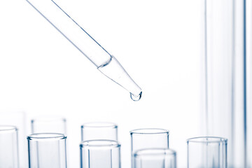 pipette with a drop and scientific laboratory test tubes in a research laboratory.