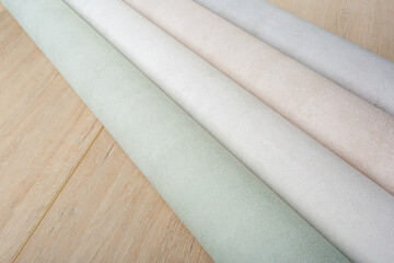 rolls of multi-colored paper wallpaper on a wooden table