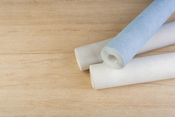 rolls of multi-colored paper wallpaper on a wooden table