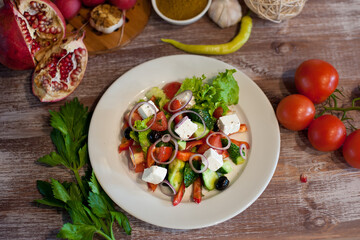 Greek salad on a white plate. Good nutrition. National cuisine. Salad with cucumbers, tomatoes, feta cheese, olives and herbs