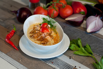 cheese soup with chicken breast on a white plate . beautiful serving on a wooden table
