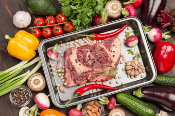 Raw meat. Marbled beef steak in metal baking dish with chili peppers.