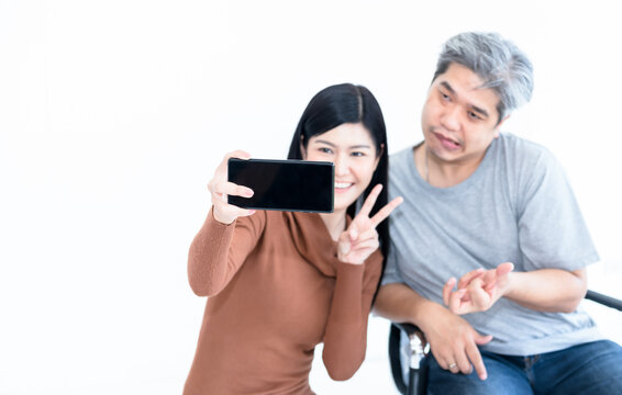 Blurred soft images of Asian wife and husban Who is paitiant from nervous system and paralysis or hemoplegia, they are using mobile phone for application Video call On white background