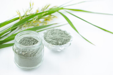 Green cosmetic clay for face and hair care in a glass jar on a white background. Natural cosmetics, spa care concept.