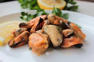 Close-up of Mussels with lemon and parsley on a white plate 
