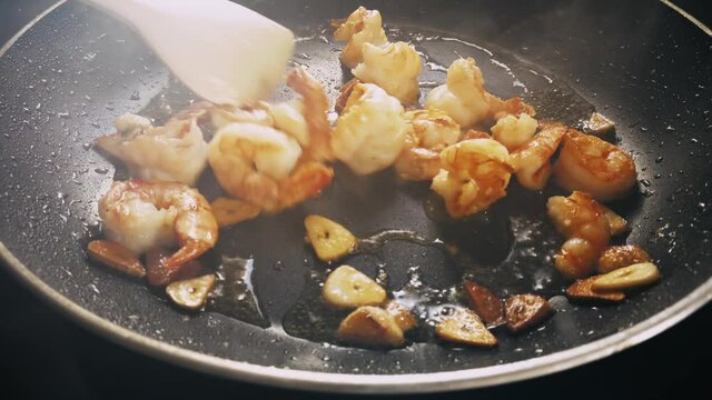Garnelen und Knoblauch werden in einer Bratpfanne gebraten und brutzeln in hei&szlig;em &Ouml;l