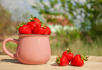 a ceramic cup with strawberries on a table in the garden, next to the cup are strawberries