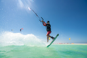 kiter does a difficult trick on a background of transparent water and blue sky