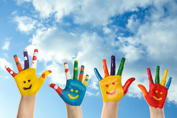 School holidays. Children with painted palms and blue beautiful sky on background, closeup